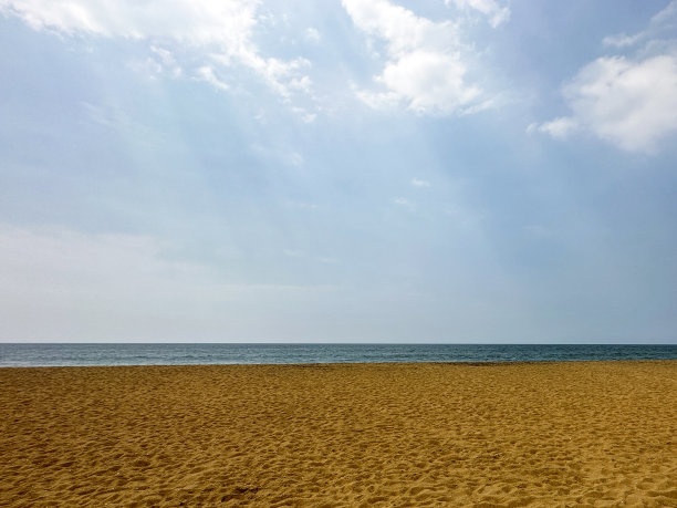 图像平静的海浪，金色的沙滩沙滩，潮汐和大海的运动，阳光冲破云层，多云的蓝色晴朗的天空，壁纸背景，重点在前景，复制空间图片下载