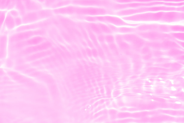 紫色的水面上泛起涟漪。散焦模糊透明粉红色透明平静水面纹理与飞溅和泡沫。水波与闪亮的图案纹理背景。图片下载