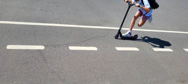 踏板车沿着轨道行驶，上面有自行车的标记，可以看到腿。图片下载