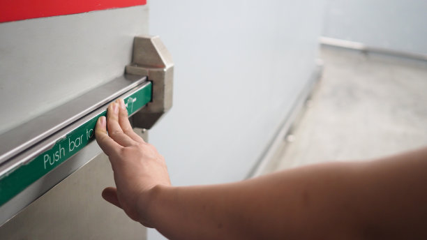 用于紧急疏散的消防出口的防火门把手。手是推杆的。图片下载