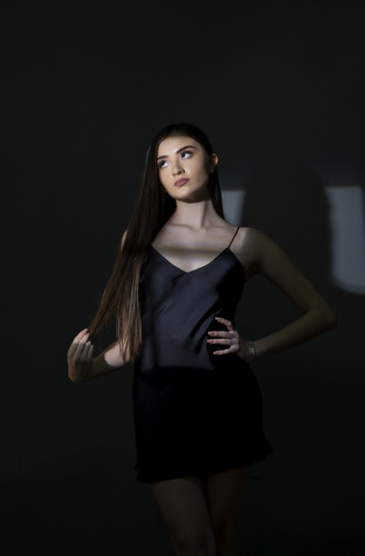 美丽的年轻女子透过窗户望着窗外，脸上有阴影图片下载