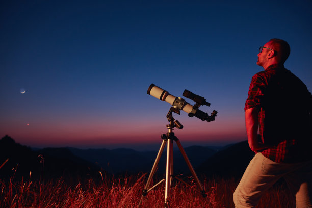 用望远镜观察星空和新月的天文学家。图片下载