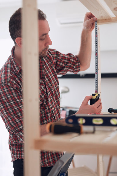 一个人在公寓里组装新的木架子和家具。图片下载