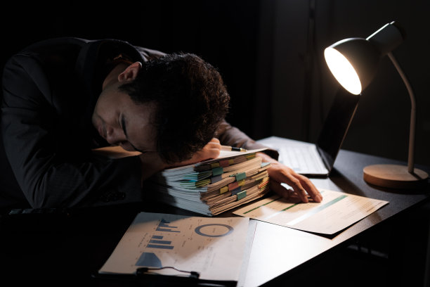 疲惫的商人在昏暗的办公室里用笔记本电脑工作到很晚图片下载