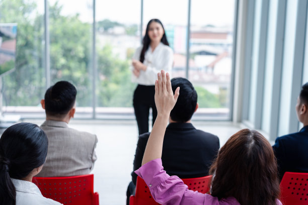 商务人士在研讨会上举手。在会议中，在商务会议室和研讨课上，举手要求回答问题。图片下载