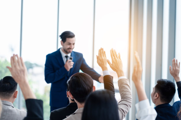 商务人士在研讨会上举手。在会议中，在商务会议室和研讨课上，举手要求回答问题。图片下载