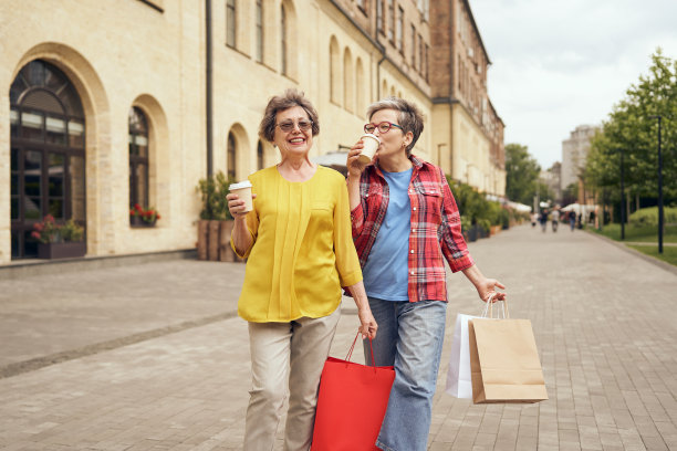 成熟的女人走在城市的街道上，喝着咖啡，购物后玩得很开心。季节性销售图片下载