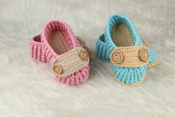 白色毛绒毯子上的粉色和蓝色针织靴。性别党观念观念。婴儿的第一步是给女孩或男孩穿靴子。图片下载