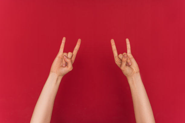 女性的手在红色的背景下显示摇滚符号图片下载