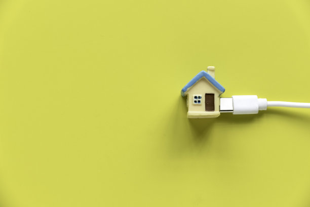 住宅和公用设施概念。微型房子连接在黄色背景上的白色电缆上图片下载