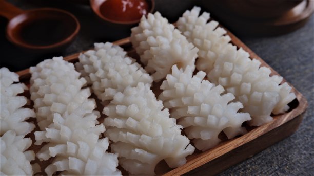 新鲜的鱿鱼放在方形木盘上，经过清洗和切割，像花一样，在小木勺上放上一些酱和盐。图片下载