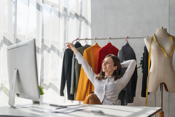 在设计工作室工作的时装设计师。老练、自信、微笑的女设计师望着窗外的肖像图片下载