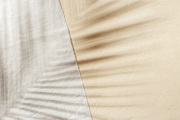 夏天的背景，俯瞰海滩浴巾在沙滩上与棕榈叶的太阳阴影。夏天唯美的照片淡米色，复印空间，度假休闲的概念。俯瞰沙滩。图片下载