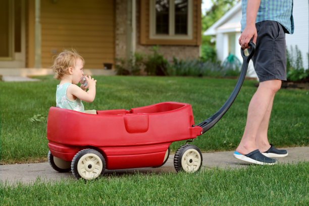 漂亮的年轻女孩坐在户外的一辆红色马车上。女孩正在喝水。图片下载