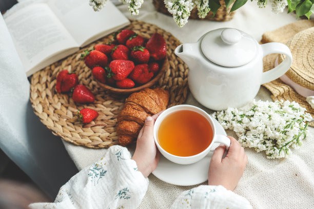 手中一杯茶，草莓和鲜花，夏日早餐概念图片下载