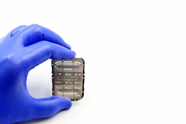 戴着蓝色手套的手拿着手机键盘或旧电子设备图片下载