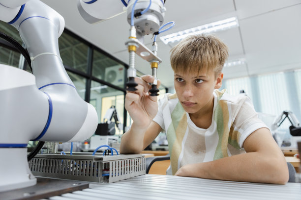 男生白种人教育电子机械臂放在教室桌子上。学习创新机器人电子未来人工智能。系统技能培训。STEM教育理念。图片下载