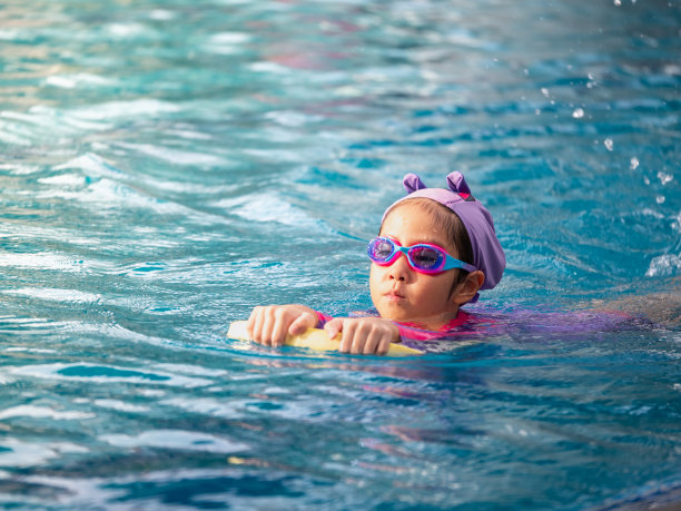 亚洲儿童或小女孩穿着泳装在游泳池学习，在踢板上学习和训练游泳图片下载