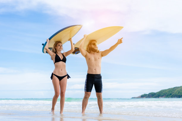 情侣周末在沙滩上玩冲浪板活动，运动极致健康的生活方式理念。图片下载