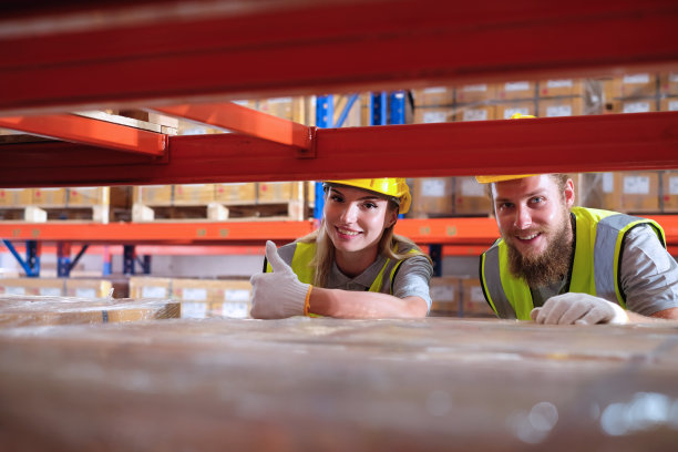 女工业工厂工程师竖起大拇指，男工程师微笑着检查仓库货架上的货物。图片下载