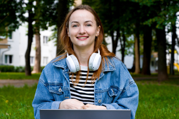 公园里快乐的红发女性拿着笔记本电脑的特写。学院，大学，高中生。图片下载