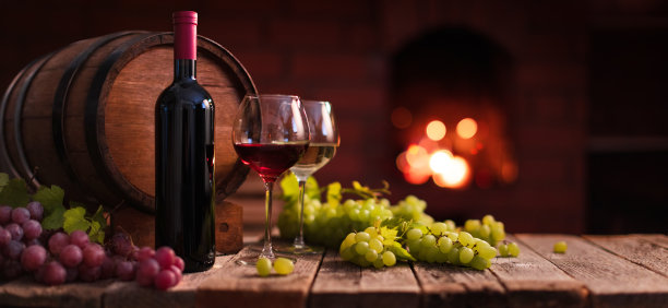 红葡萄酒和白葡萄酒。一杯以自制壁炉为背景的红酒和葡萄图片下载