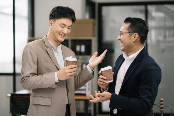 男同事在工作休息时站在工作区域拿着咖啡杯微笑着各种业务团队愉快地交谈，享受着办公室的友好关系。图片下载