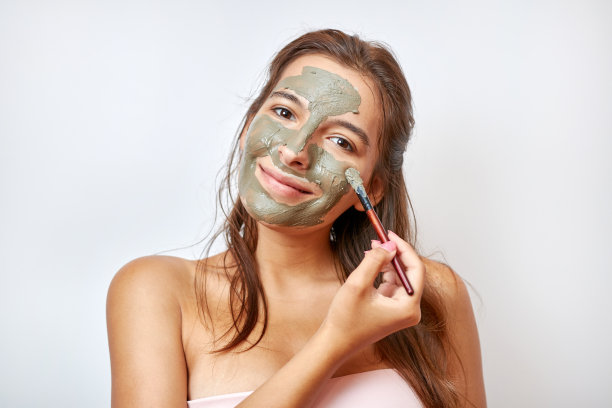 这个女孩用蓝粘土做面部护理。美容理念，护肤化妆品，整容。美容院。皱纹去除。图片下载