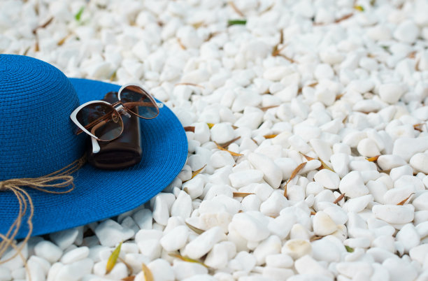 在海滩上戴蓝帽子，涂防晒霜，戴墨镜。图片下载