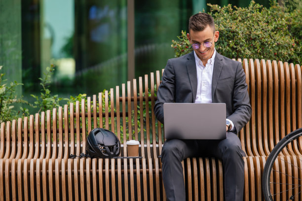 年轻帅气的商人一边用笔记本电脑一边喝咖啡图片下载