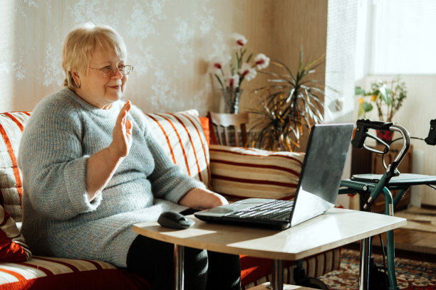 资深成熟率真的白种女人在家里看着笔记本电脑屏幕。快乐的老年金发女郎通过互联网与家人进行在线视频通话。老年科技理念。图片下载