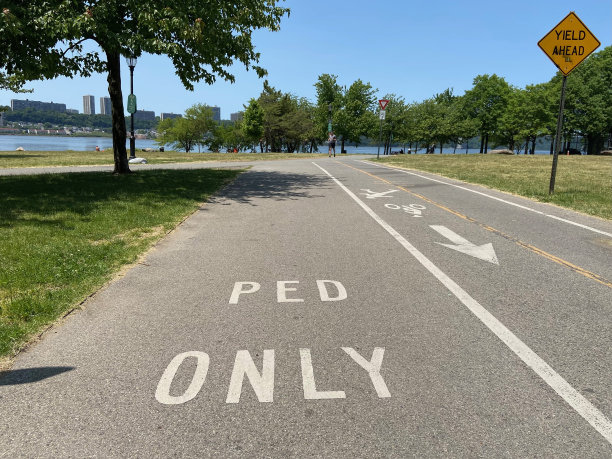 纽约河滨公园的自行车和直排轮滑道旁边的曼哈顿滨水区绿道上的行人专用道上的“自行车专用”标志图片下载