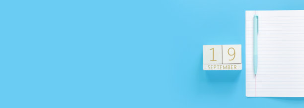 9月19日。木制日历上的蓝色背景与一个开放的记事本，顶视图图片下载