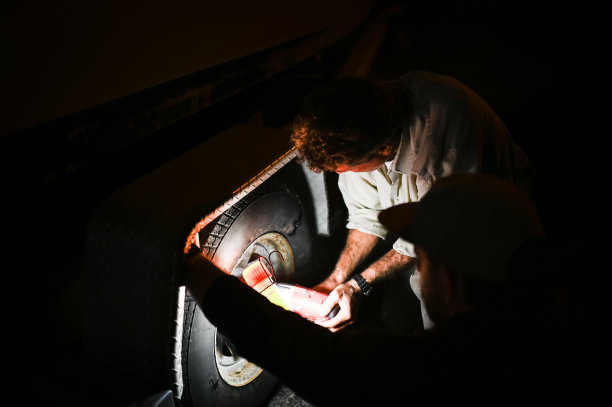 一个人在黑暗的夜晚开着应急灯在汽车里换轮胎图片下载