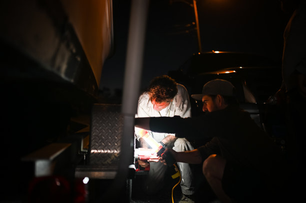 一个人在黑暗的夜晚开着应急灯在汽车里换轮胎图片下载