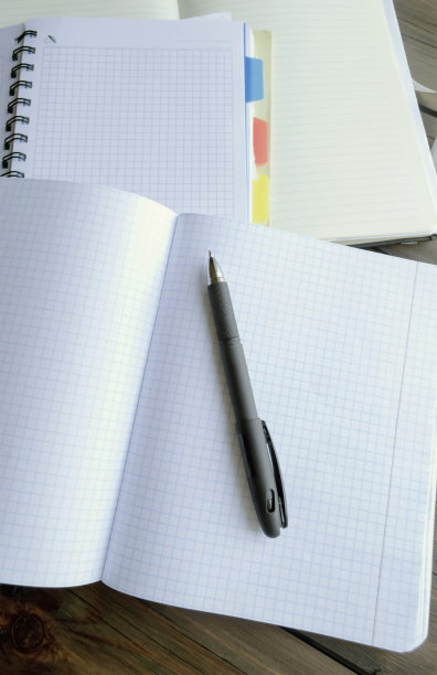用笔打开笔记本。学校的教育——木桌上的笔和笔记本。图片下载