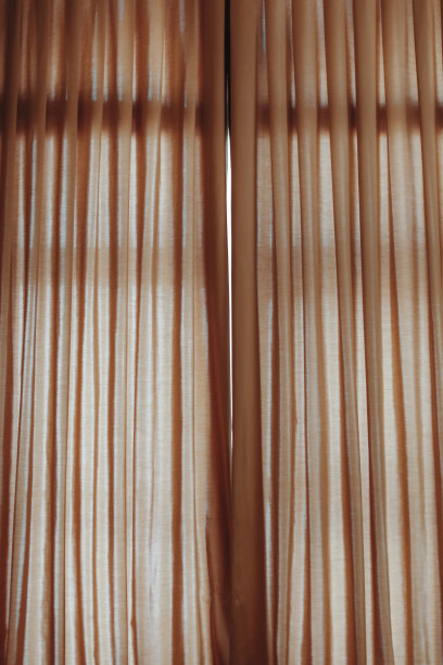 半透明的棕色直窗帘覆盖着窗户。图片下载
