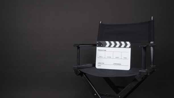 在黑色背景的视频制作，电影，电影工业中使用的拍板或拍板或电影板与导演椅。图片下载