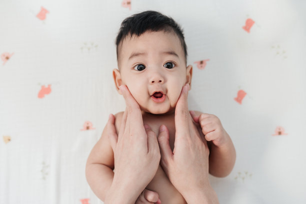 可爱的亚洲宝宝。爱的哺育，亚洲妈妈的手抚摸可爱宝宝的脸颊，象征爱，信任，宝宝的皮肤护理图片下载