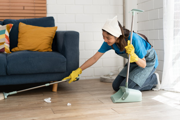 一名身着工作服的亚洲女工在家里用簸箕扫建筑垃圾图片下载