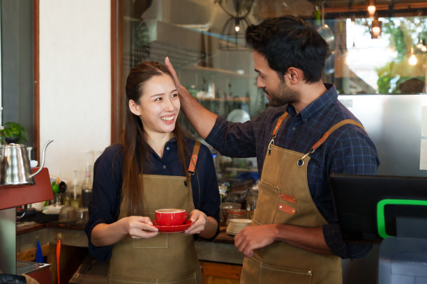 店主是一名亚洲男子，当时正举着一杯由妻子咖啡师冲泡的咖啡，想要品尝一下咖啡的味道，以便丈夫在面包店咖啡馆卖东西时喝咖啡。图片下载