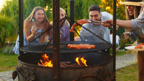 一群不同种族的人在一起玩得开心，互相交往，在户外聚餐时烧烤。在一个温暖的夏日，家人和朋友聚集在他们的房子外面。图片下载