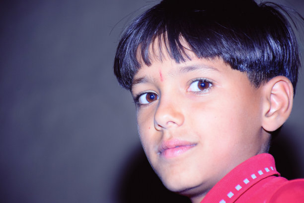 可爱的小印度亚洲男孩穿着红衬衫微笑。图片下载