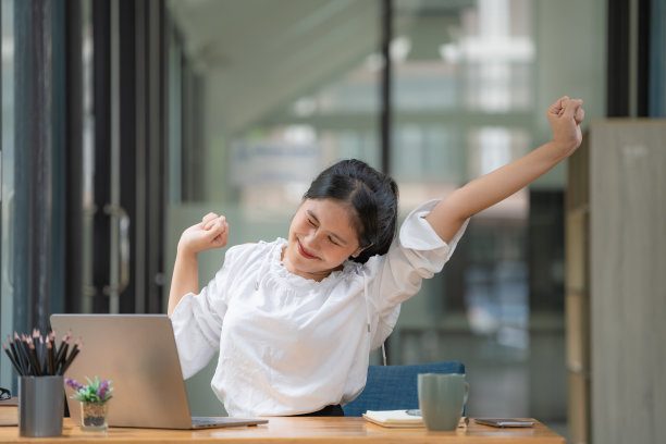 亚洲女商人，年轻迷人，伸展着肩膀和手臂的肌肉。由于久坐和工作，给商务人士和办公室综合症的概念。图片下载