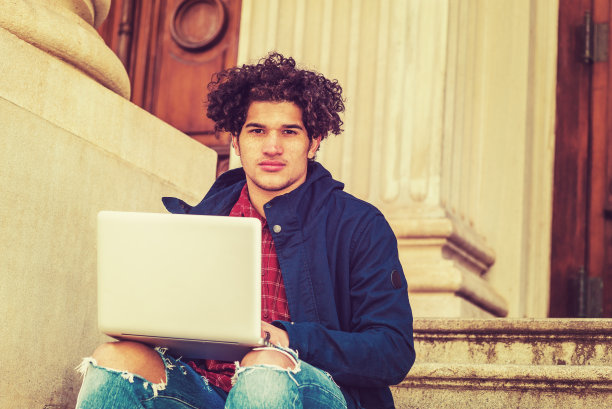 年轻的大学生在纽约办公大楼外用笔记本电脑工作图片下载