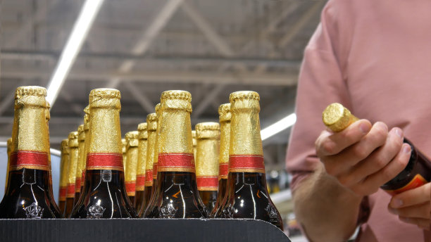 许多金箔玻璃啤酒瓶的特写，一位男性买家正在检查其中一个图片下载