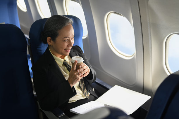 愉快的成熟的女商人喝着咖啡，望着窗外的飞机图片下载