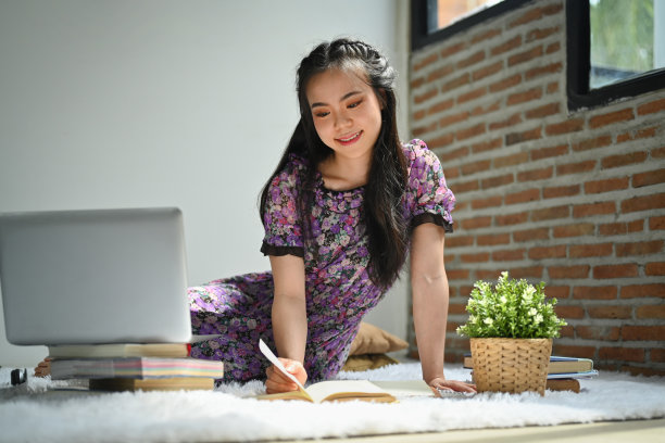 漂亮的年轻女子穿着休闲服，坐在客厅的地毯上看书。人，休闲，生活理念图片下载