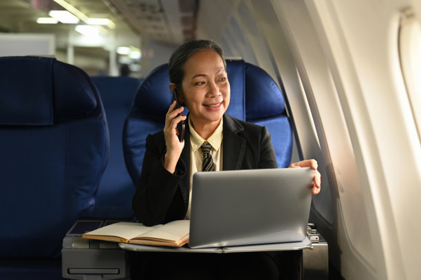 成功成熟的女商人一边打电话一边看着飞机窗外图片下载
