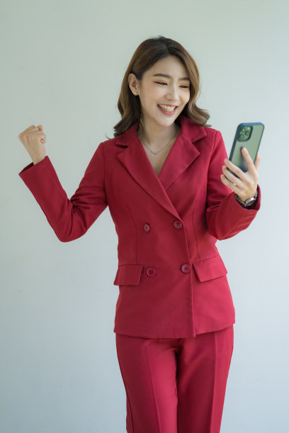 漂亮可爱的经理女士成功的商业亚洲女性在白色背景的红色西装。手持和使用移动智能手机或手机。图片下载